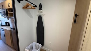 Un espace dédié à la lessive, équipé d’un étendoir, d’un fer à repasser et d’un panier.