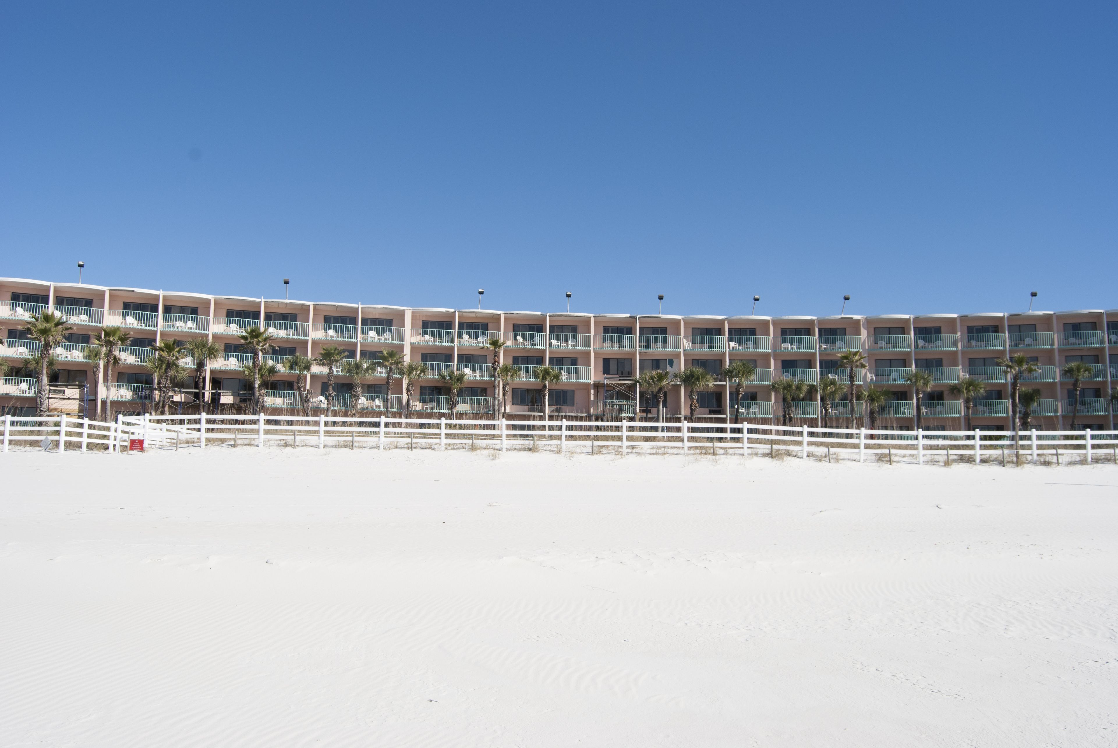 A beachfront hotel with multiple balconies and palm trees.