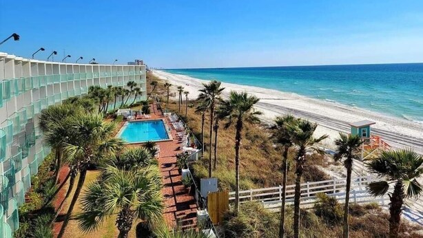 A resort with a pool, beach access, and palm trees. - Casa Loma Inn (Panama City Beach)