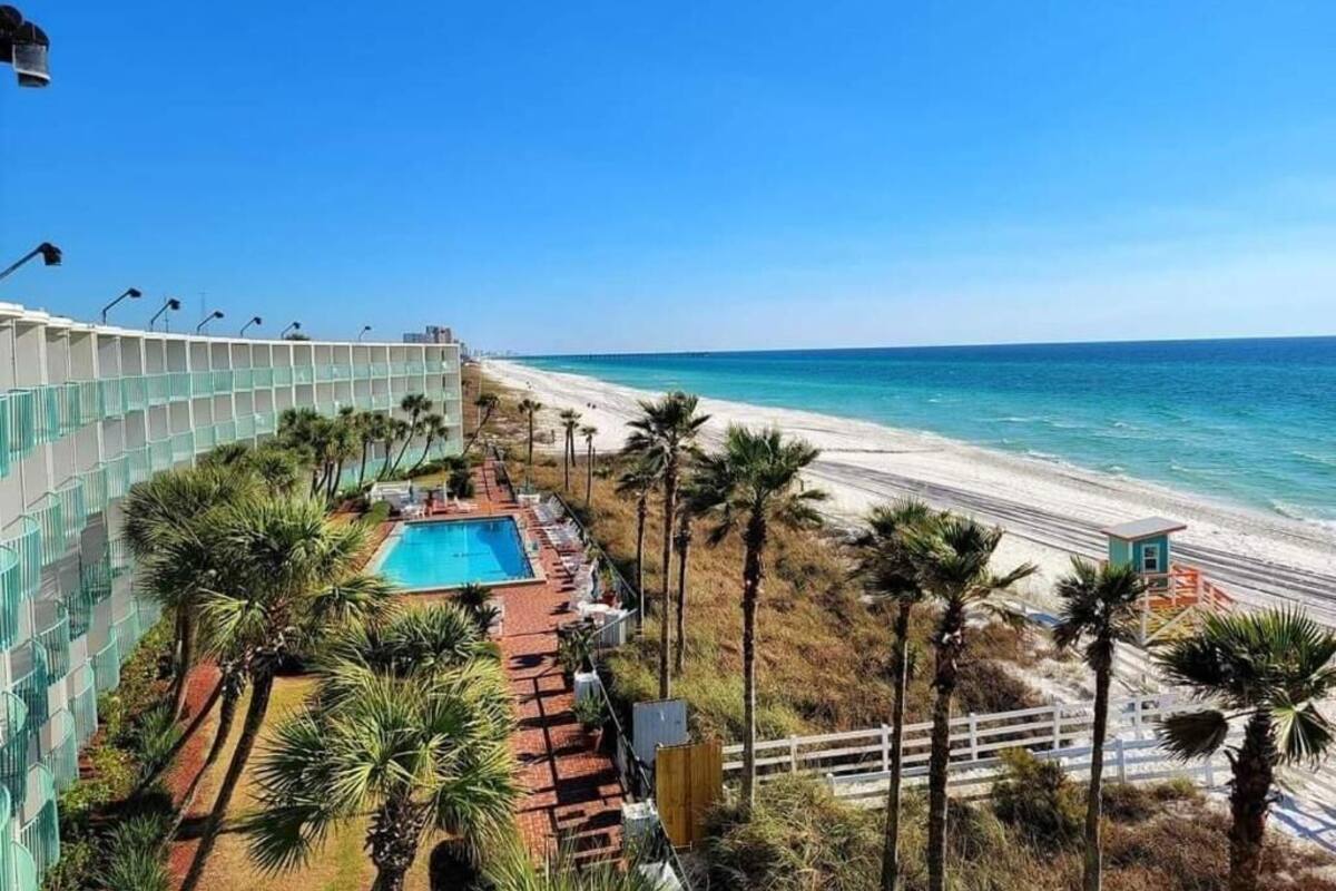 A resort with a pool, beach access, and palm trees.