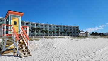 A beachside hotel with a lifeguard tower, multiple balconies, and a sandy beach.