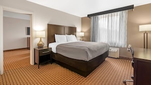 Een hotelkamer met een groot bed, bedlampen, een bureau en een raam met gordijnen.