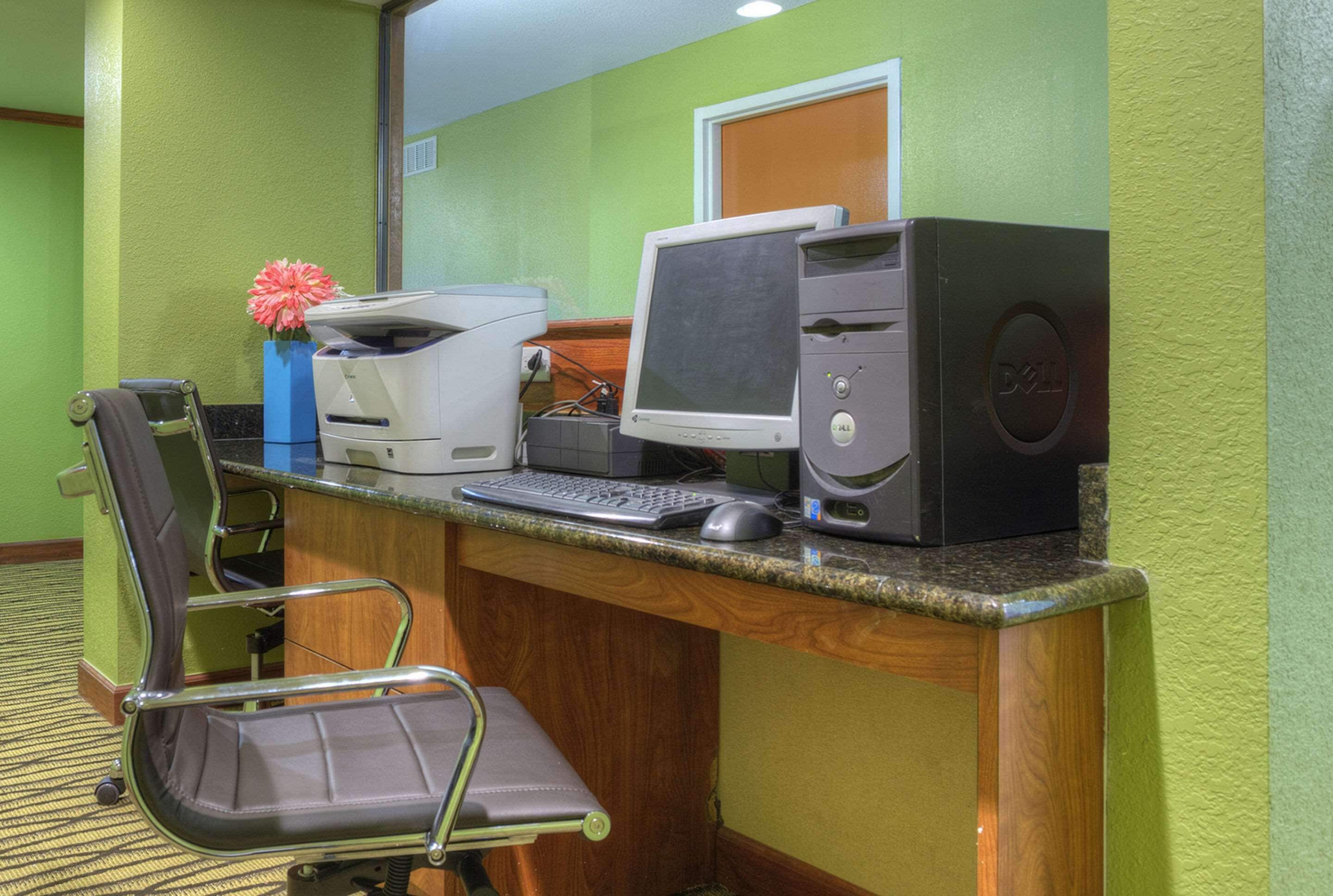 A hotel reception desk with a computer, printer, and a chair.