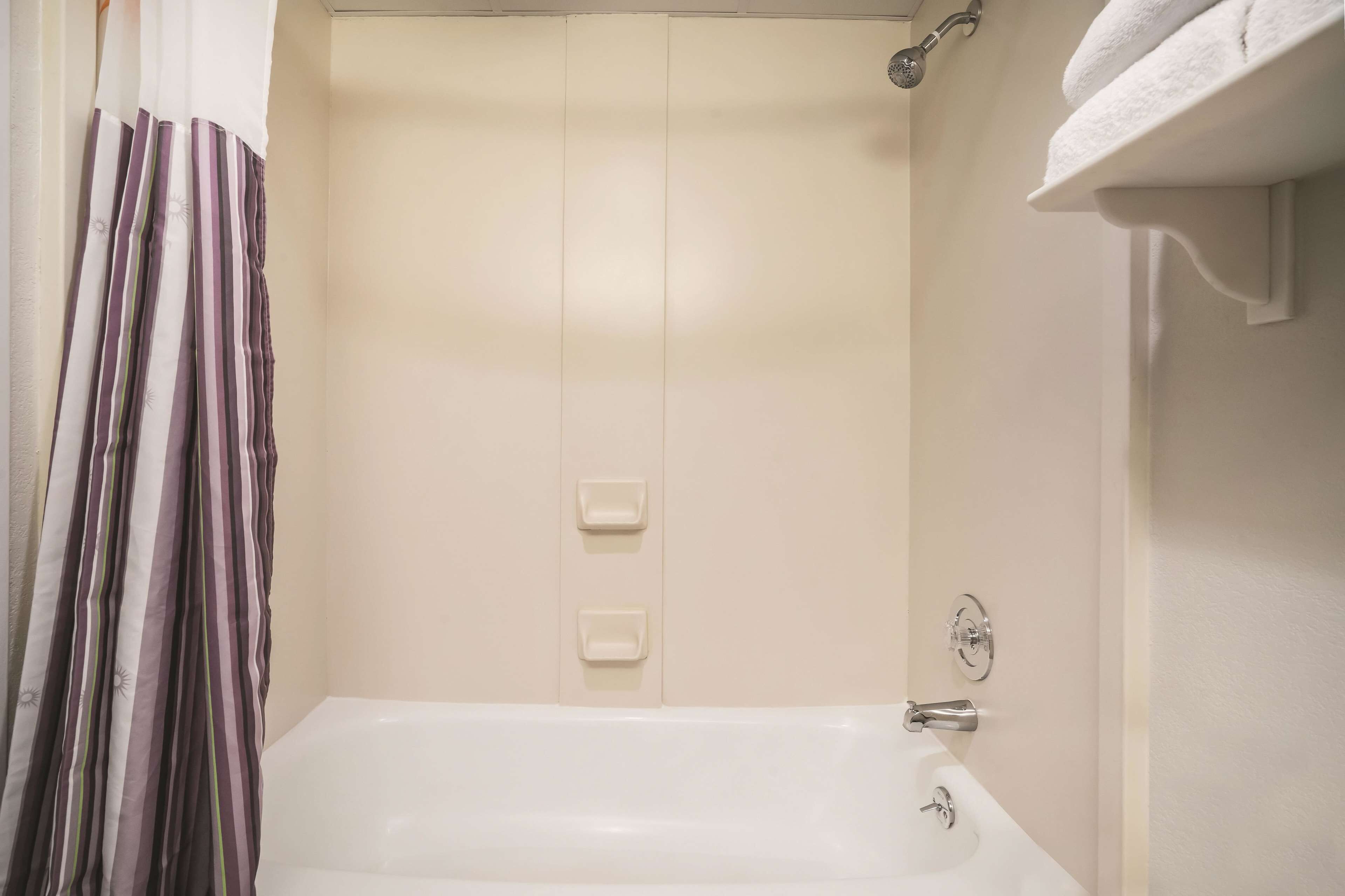 A bathroom with a bathtub, a shower curtain, and a towel rack.