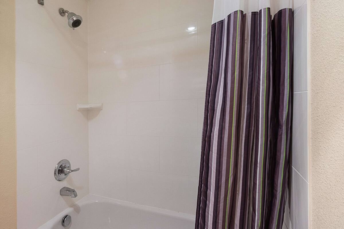 Une salle de bain avec une baignoire, une pomme de douche et un rideau de douche à rayures.