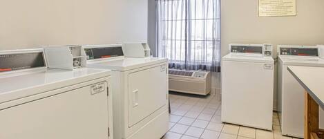 A laundry area with commercial dryers and a sign indicating guest laundry use only.