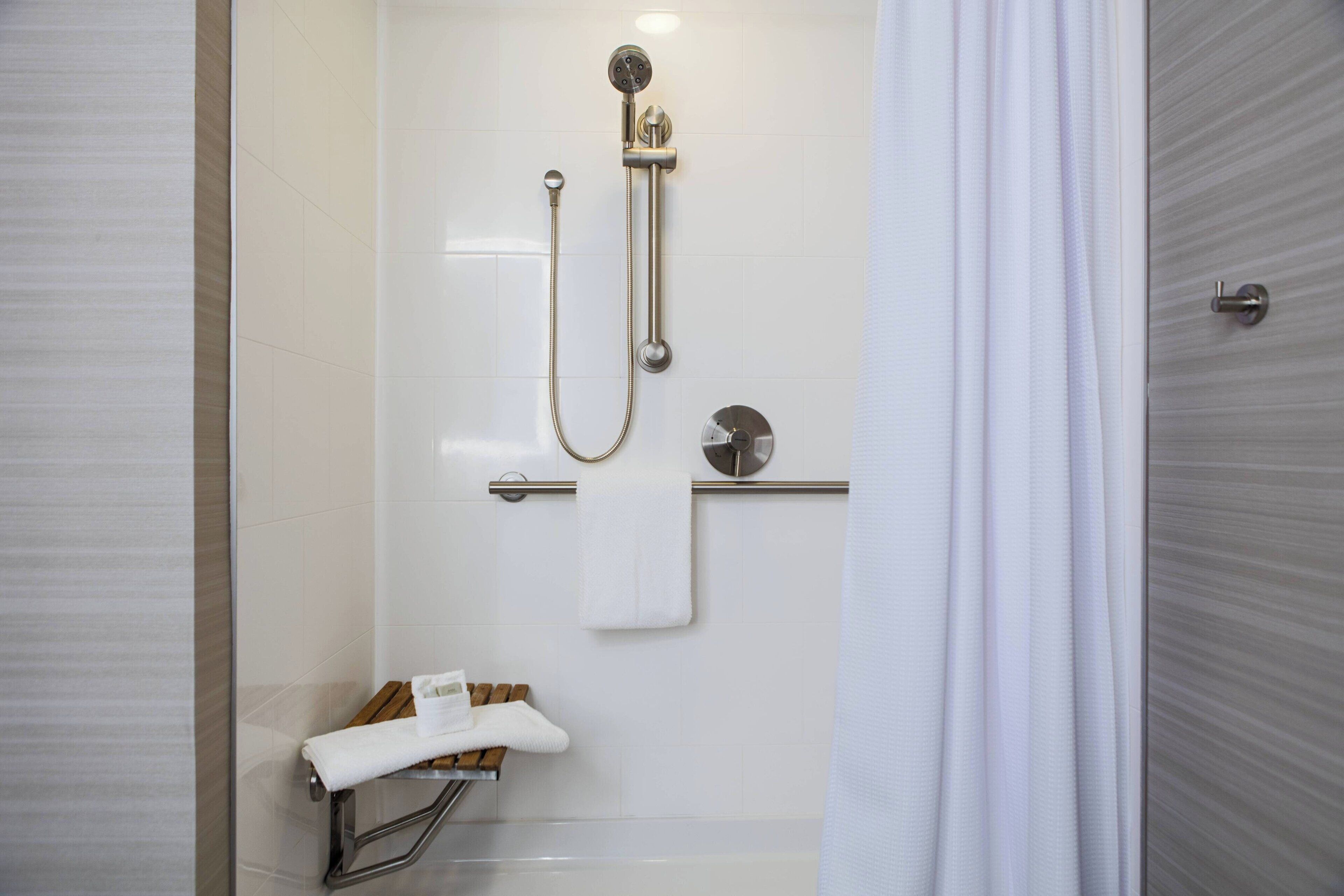 A modern bathroom with a glass-enclosed shower, a towel rack, and a toilet paper holder.