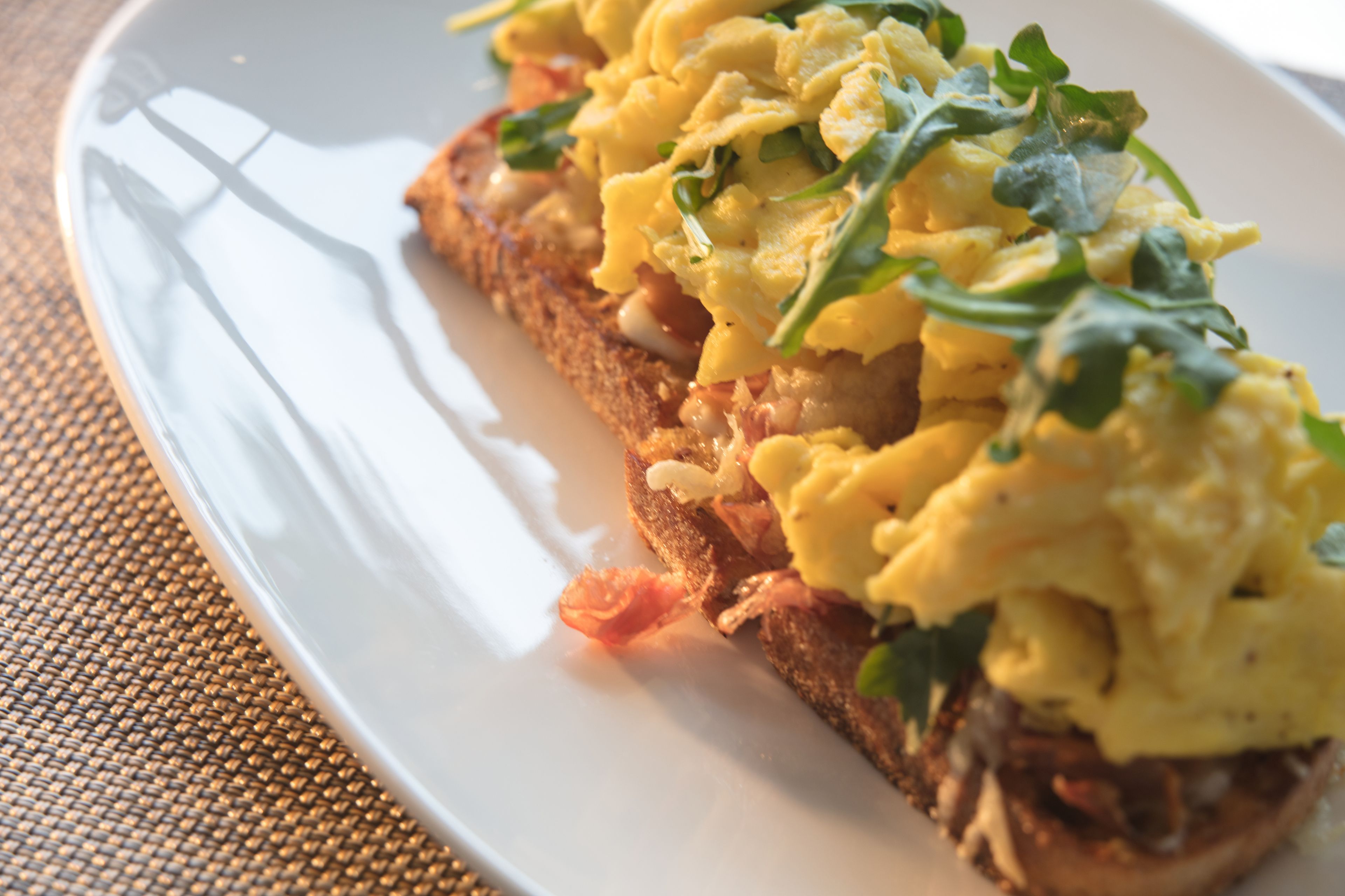 A plate with scrambled eggs on toast, garnished with greens.