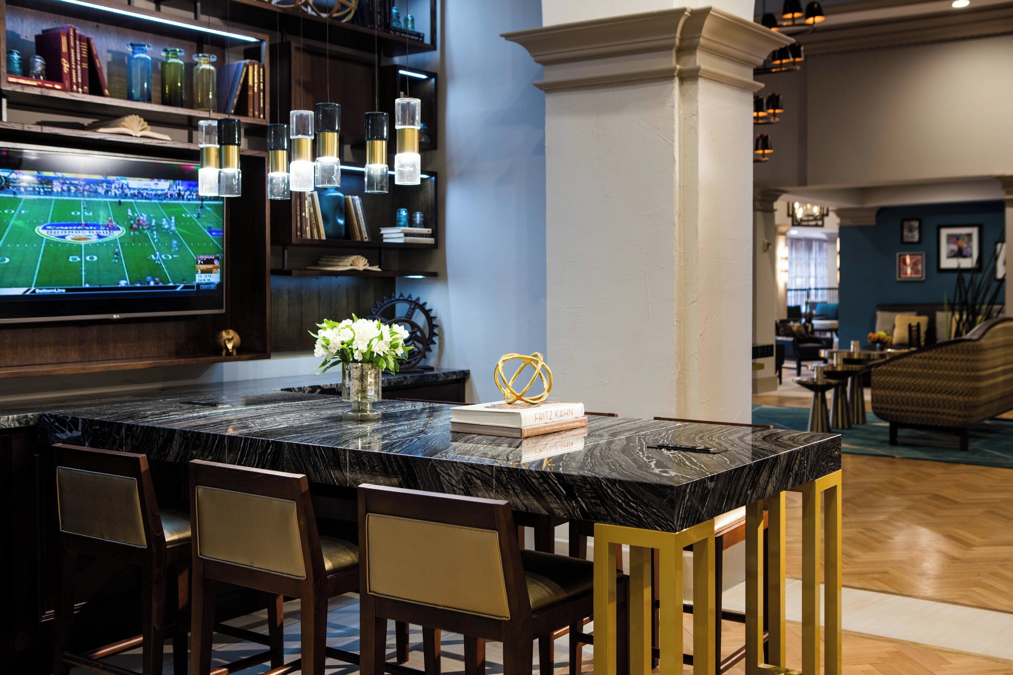 A modern kitchen with a marble countertop, a flat-screen TV, and a decorative vase.