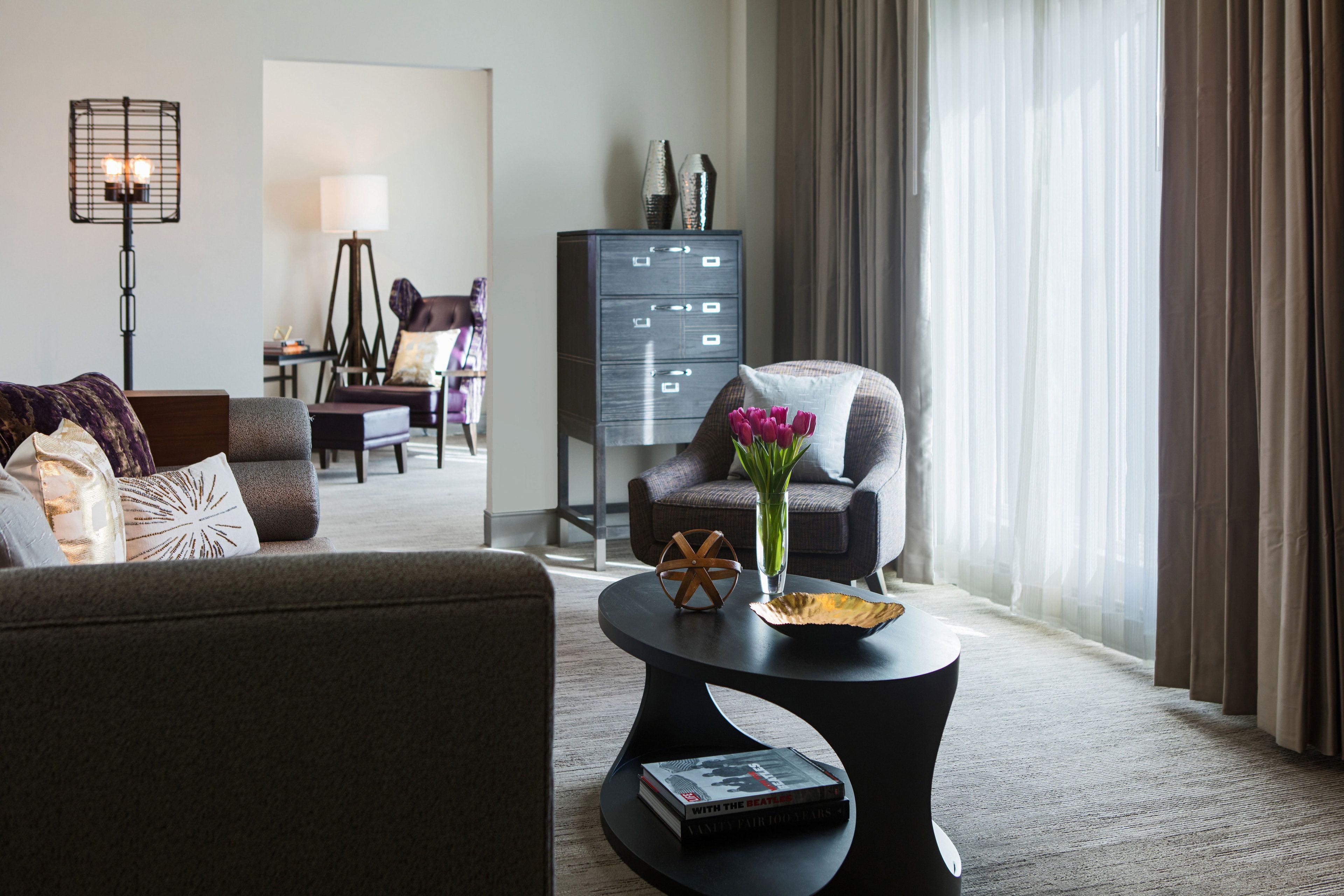 A modern living room with a sofa, armchair, and a round coffee table with a book and decorative items.