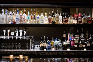 A bar with multiple liquor bottles and glasses. - Renaissance Waterford Oklahoma City Hotel (Oklahoma City)