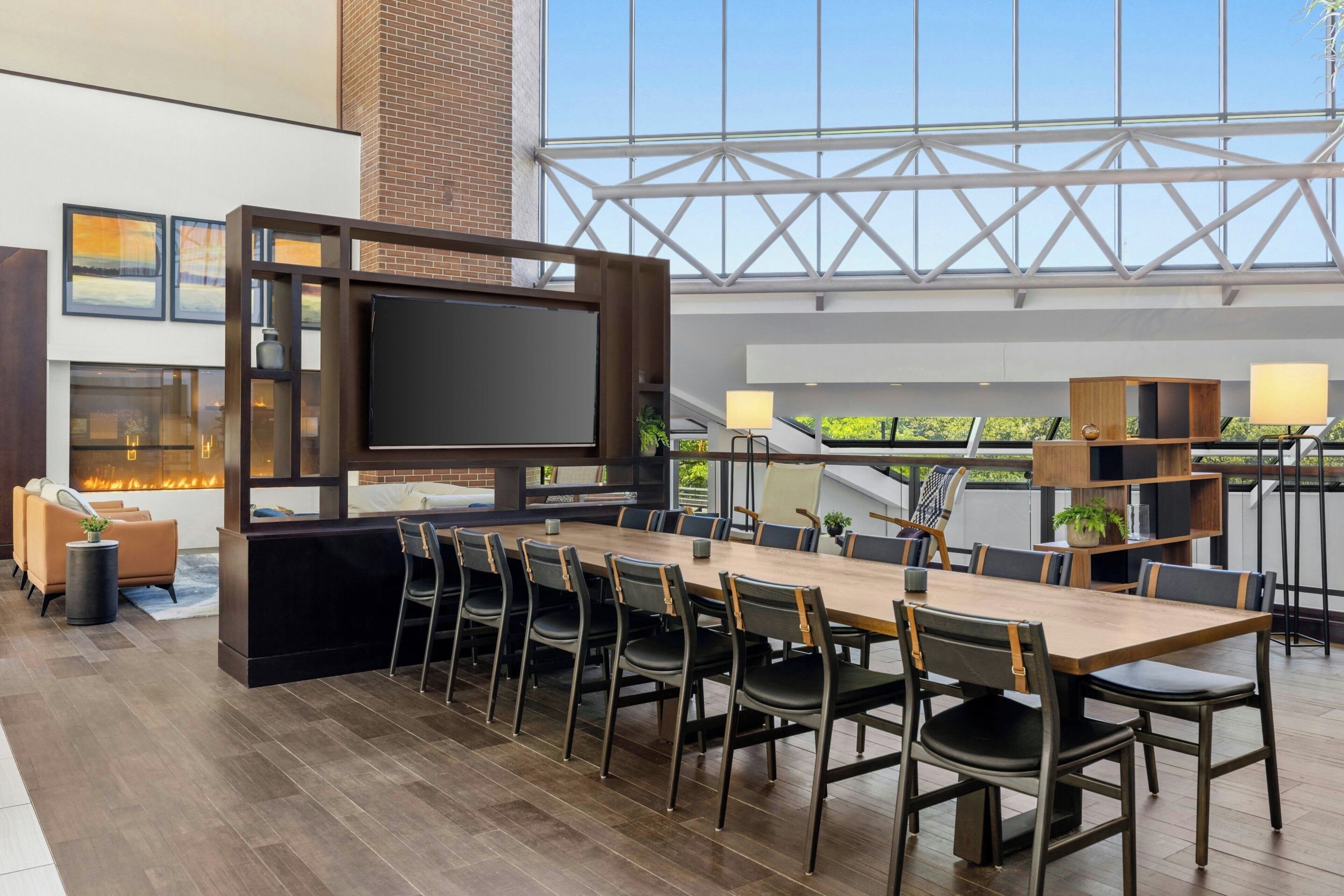 A spacious indoor area with a long wooden table, multiple chairs, a flat-screen TV, and a fireplace.
