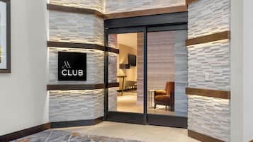 A modern interior with a stone wall, a sliding glass door leading to a room, and a sign that reads 'CLUB'.