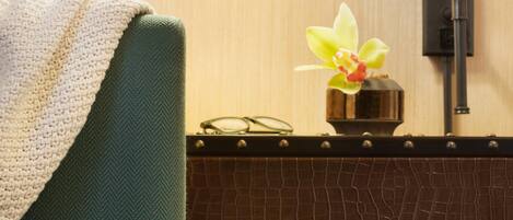 A room with a green towel, a small vase with an orchid, and a pair of glasses on a wooden surface.