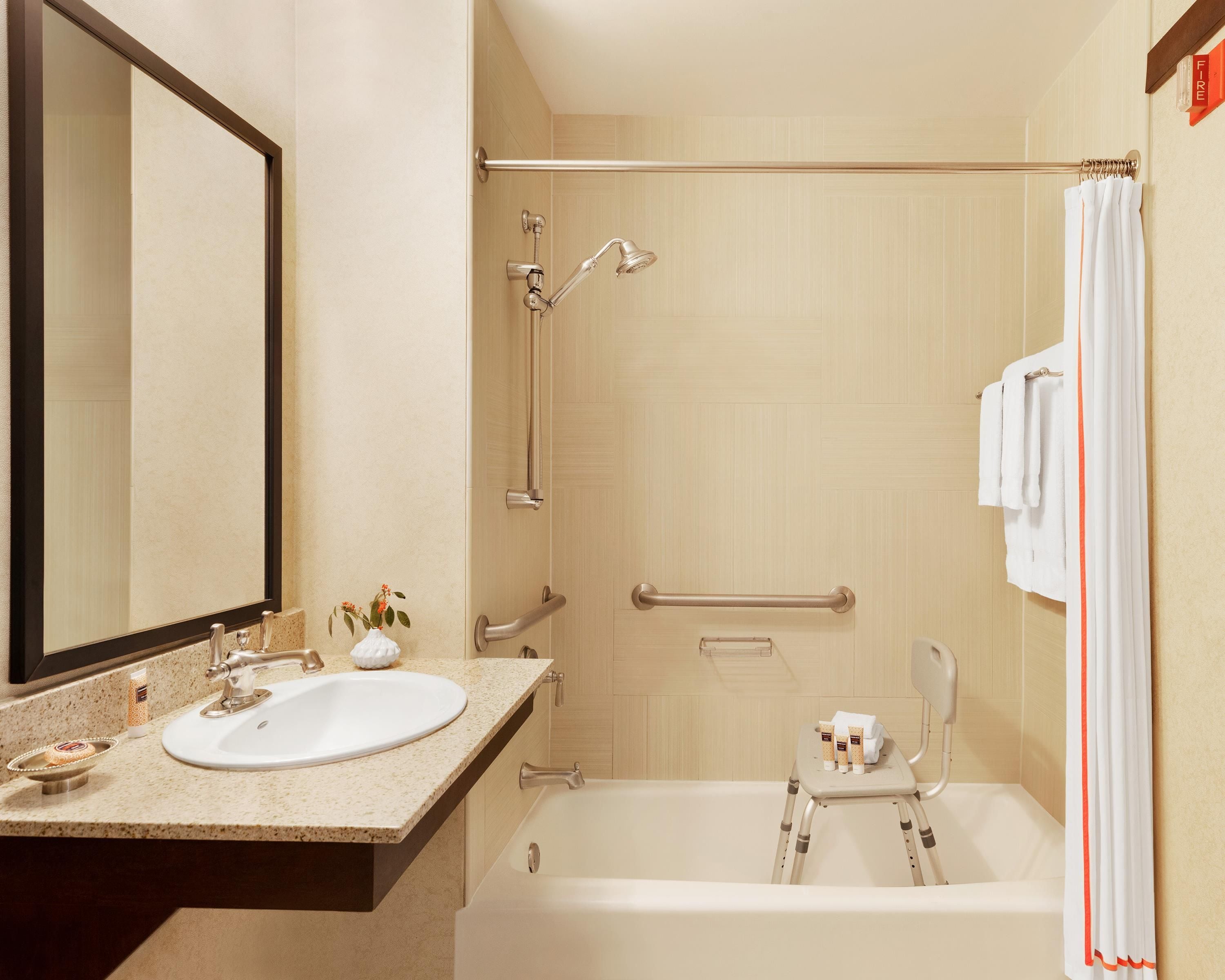 Un baño de hotel con lavabo, espejo, ducha y bañera.