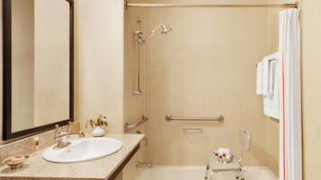 Un baño de hotel con lavabo, espejo, ducha y bañera.