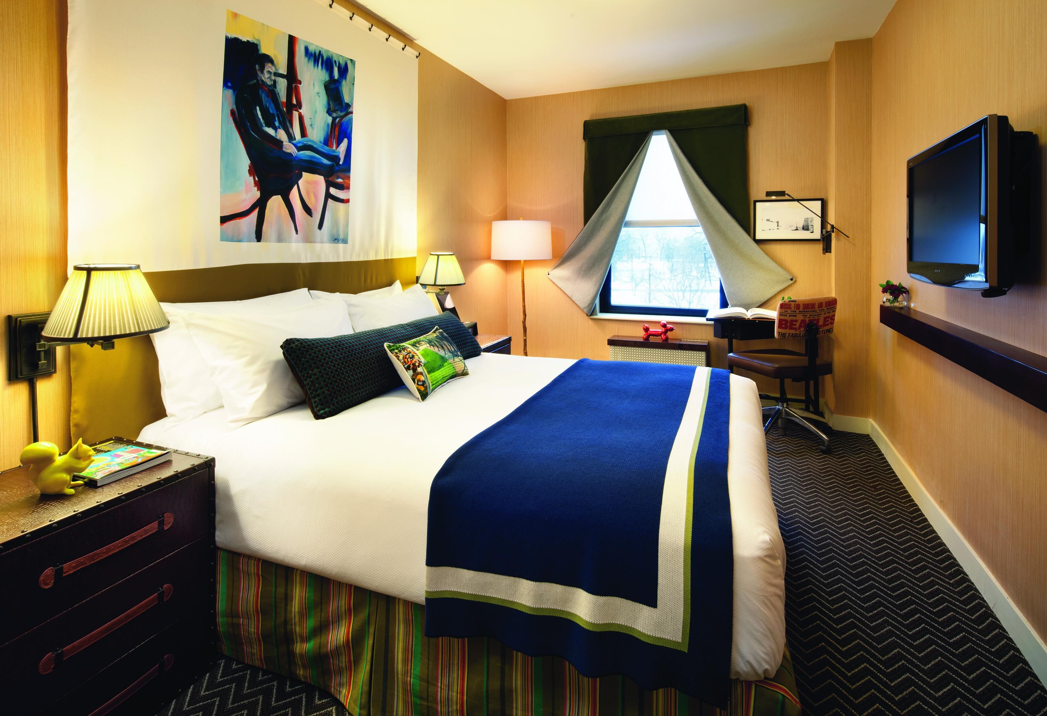 A hotel room with a bed, bedside lamps, a television, a desk with a chair, and a window with curtains.