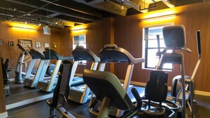 A gym with treadmills and exercise equipment, wooden walls, and a large window. - Hotel Lincoln (Chicago)