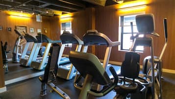 A gym with treadmills and exercise equipment, wooden walls, and a large window.