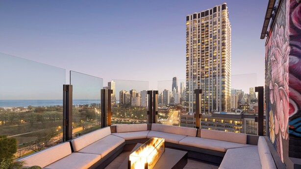 A rooftop lounge with a fire feature, seating, and a city view. - Hotel Lincoln (Chicago)