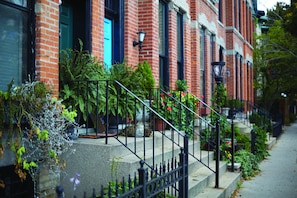 A row of brick townhouses with a black metal staircase leading to the entrance. - Hotel Lincoln (Chicago)