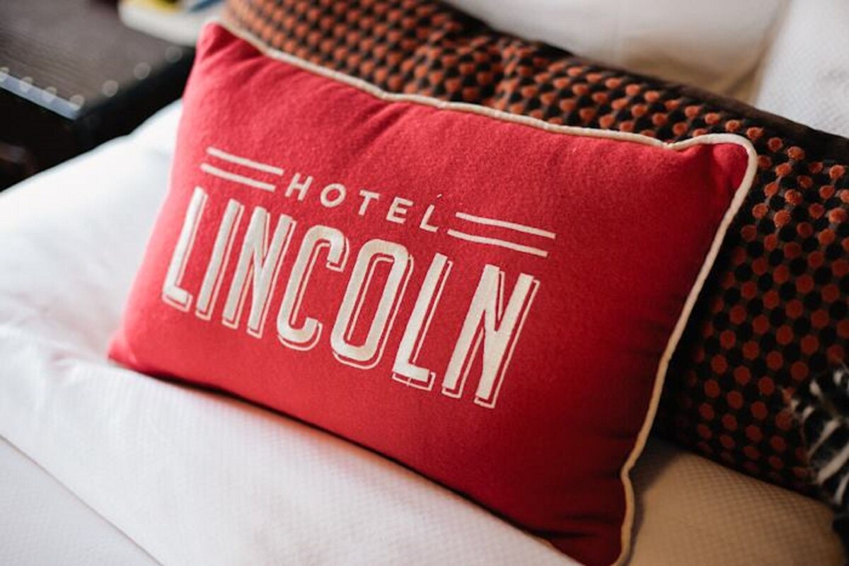 A red pillow with "HOTEL LINCOLN" text on a white couch.