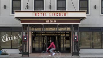 The entrance of Hotel Lincoln with a clear sign above the doors and a cyclist passing by.