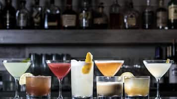 Un bar con diversos cócteles y una variedad de botellas de licor al fondo.