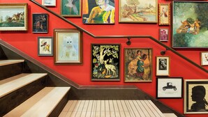 A staircase with a red wall adorned with various framed artworks. - Hotel Lincoln (Chicago)