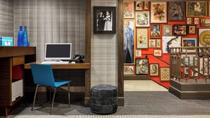 A room with a desk, chair, and a computer. There are framed pictures on the wall and a small staircase. - Hotel Lincoln (Chicago)