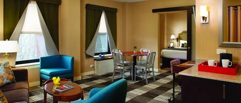 Habitación de hotel con comedor, cama, escritorio y baño.