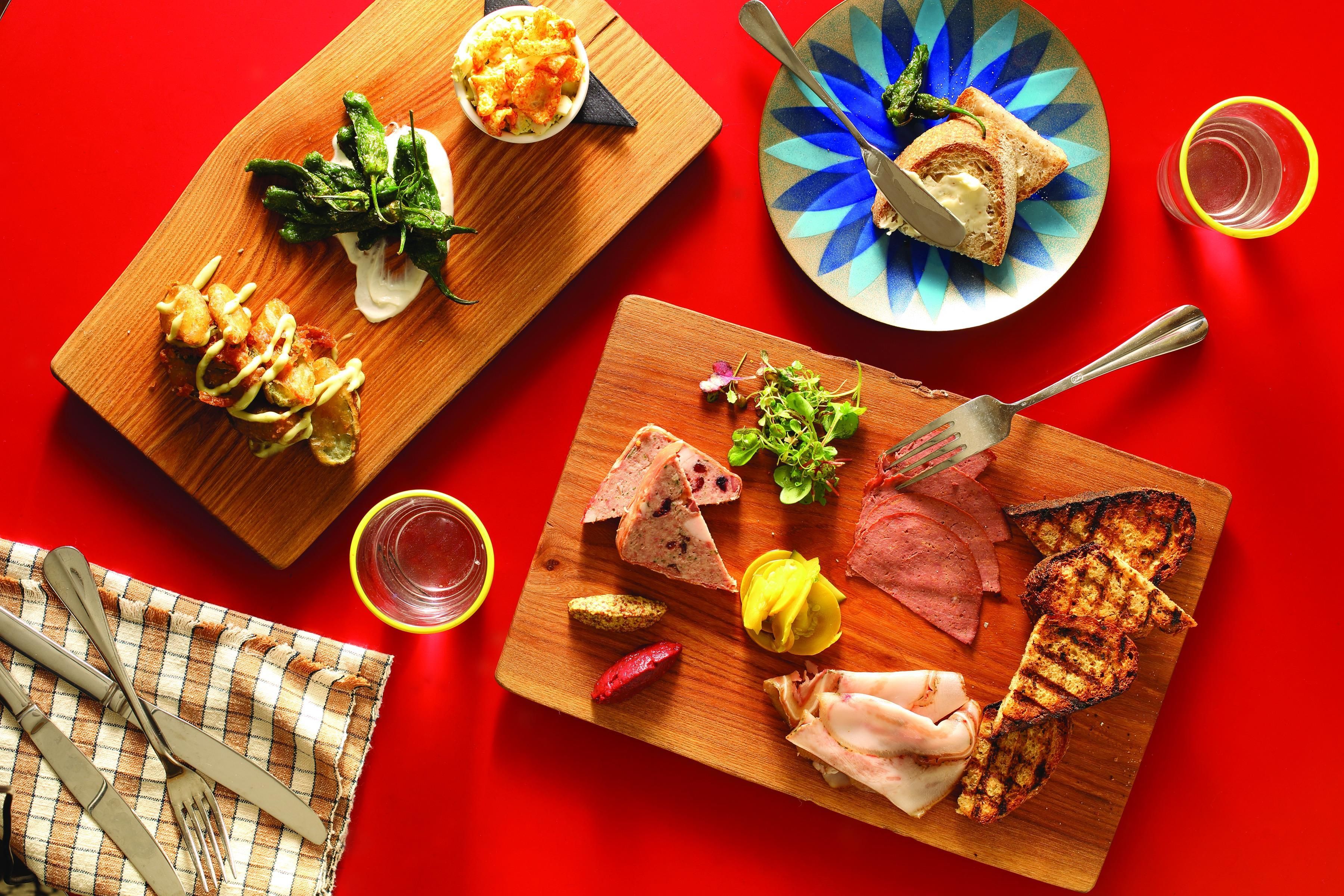 A wooden board with various food items including bread, meat, and vegetables.