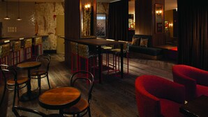 A bar area with wooden tables and chairs, a counter, and a seating area with red upholstered chairs. - Hotel Lincoln (Chicago)