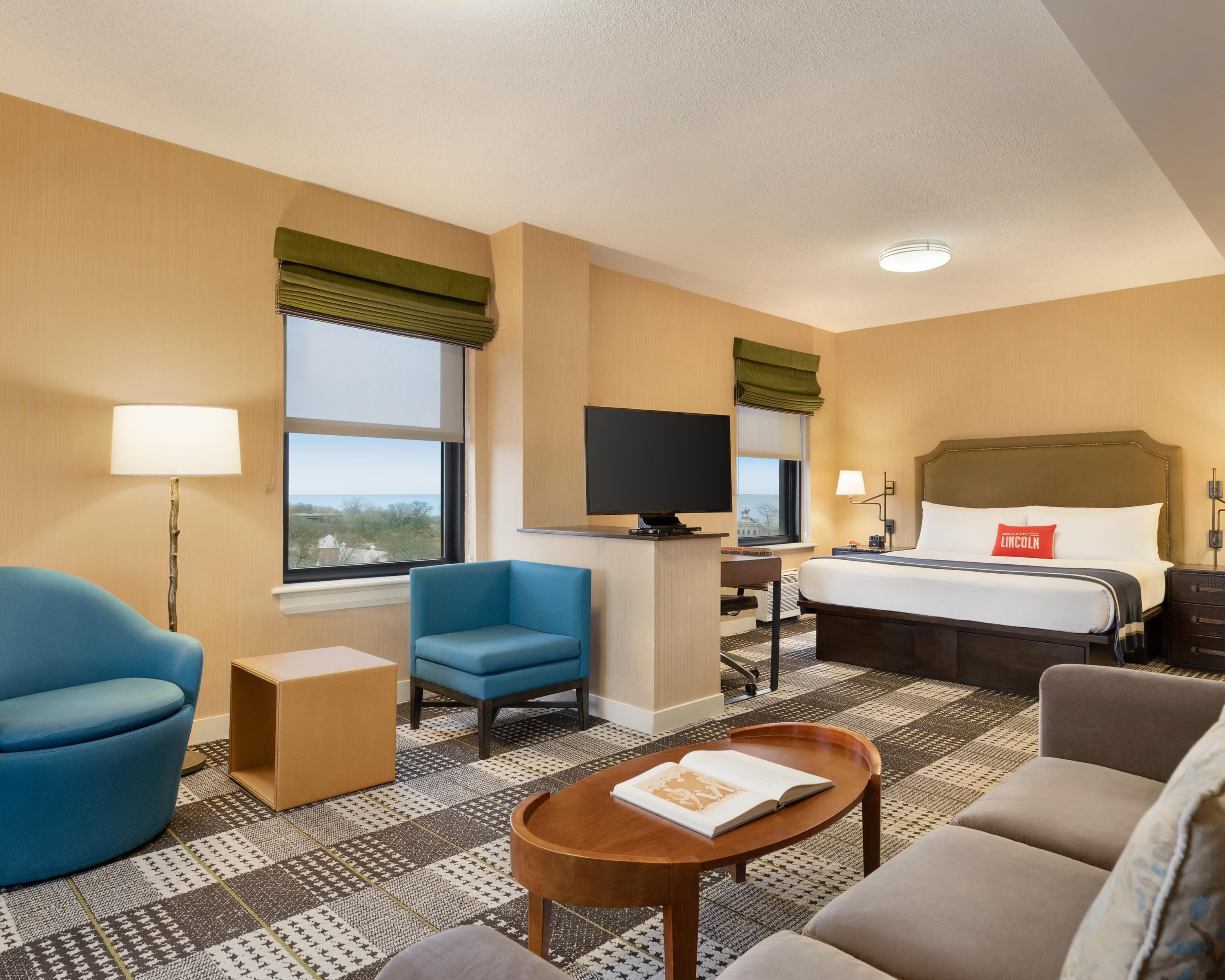 A hotel room with a bed, a television, a desk, and seating area.