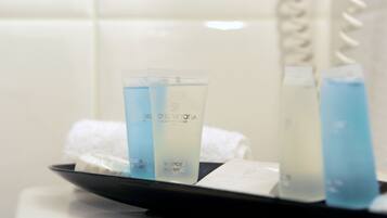 Un plateau contenant trois flacons de produits de toilette d’hôtel et une serviette blanche.