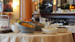 Een ontbijtbuffet met diverse etenswaren en een koffieapparaat op de achtergrond.