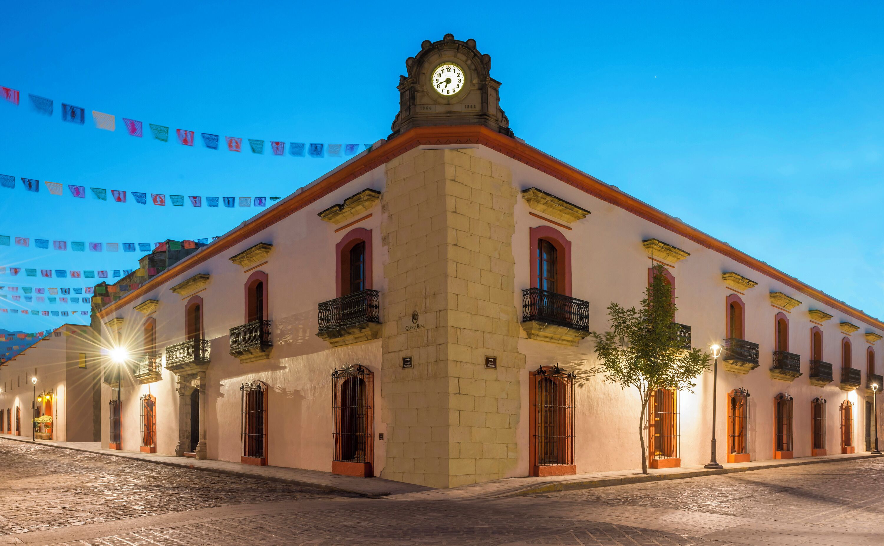 A historic building with a clock tower, multiple balconies, and a cobblestone street.