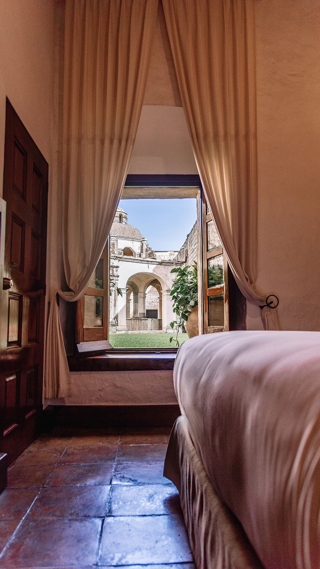 Un dormitorio con un ventanal grande, una cama y cortinas.