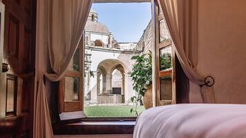 Un dormitorio con un ventanal grande, una cama y cortinas.