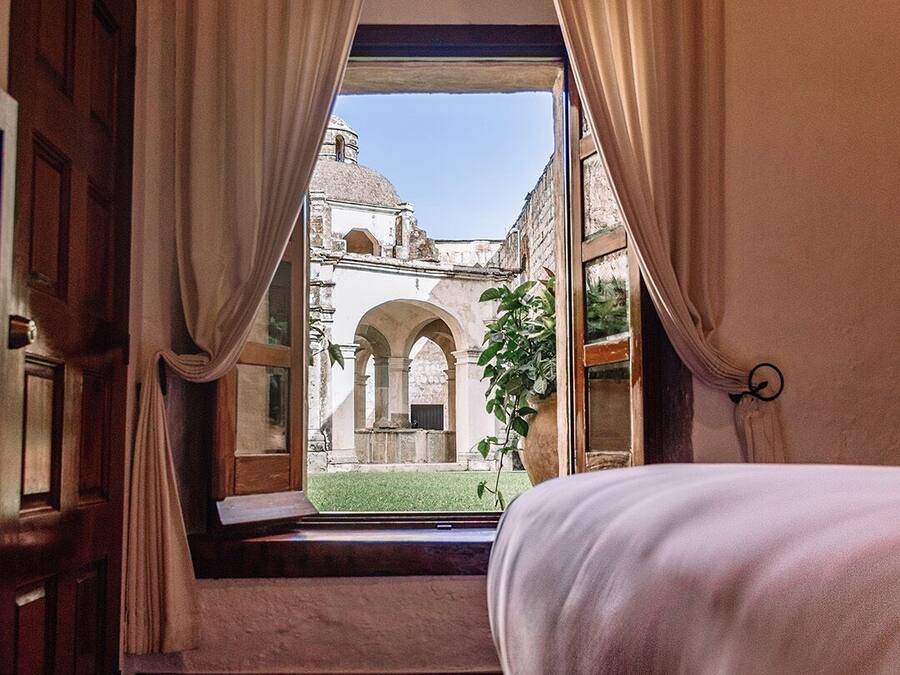 Un dormitorio con un ventanal grande, una cama y cortinas.