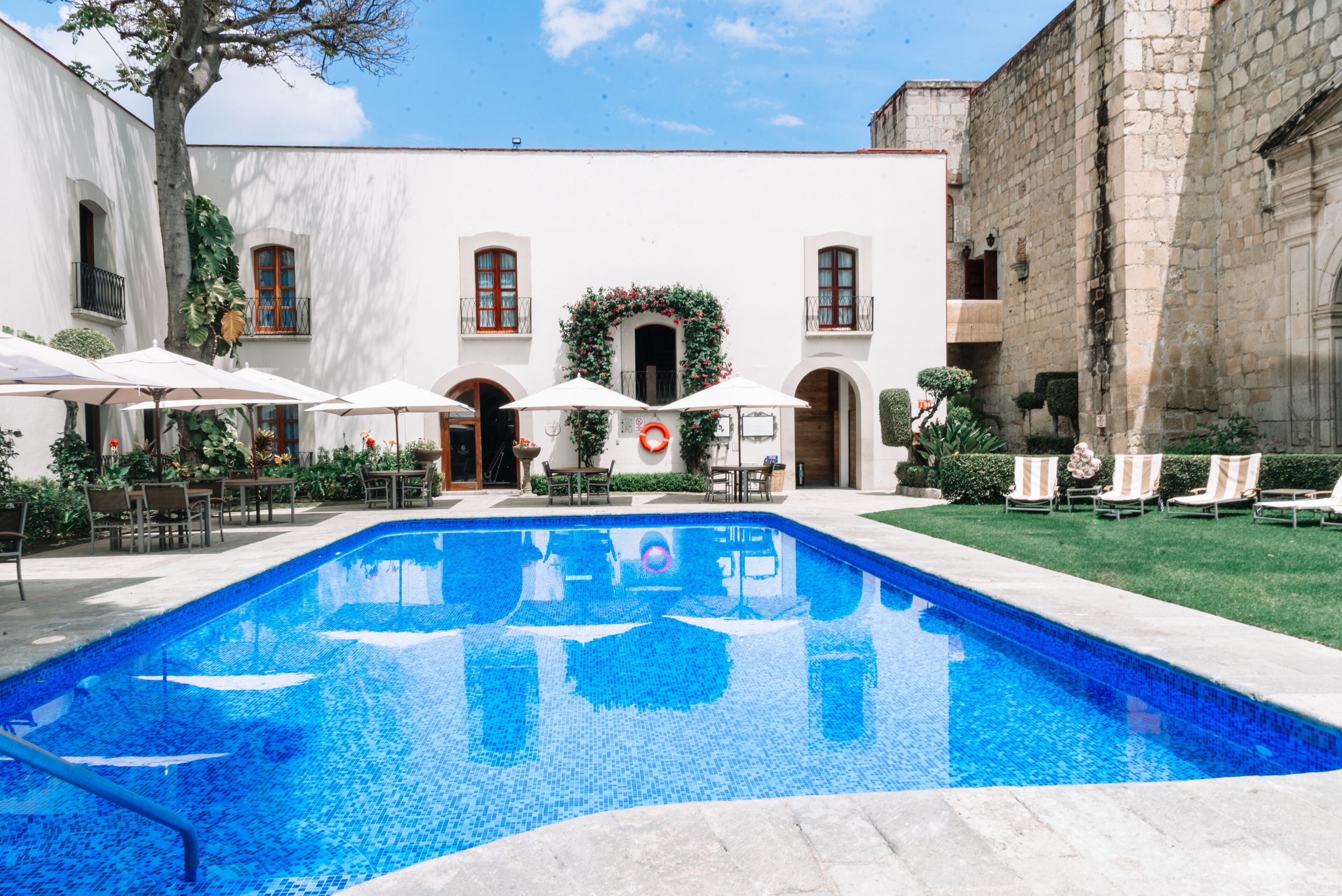 Una piscina al aire libre, sombrillas, sillones reclinables de piscina
