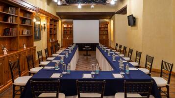 Un salón de conferencias con una mesa larga, sillas y una pantalla para proyector.