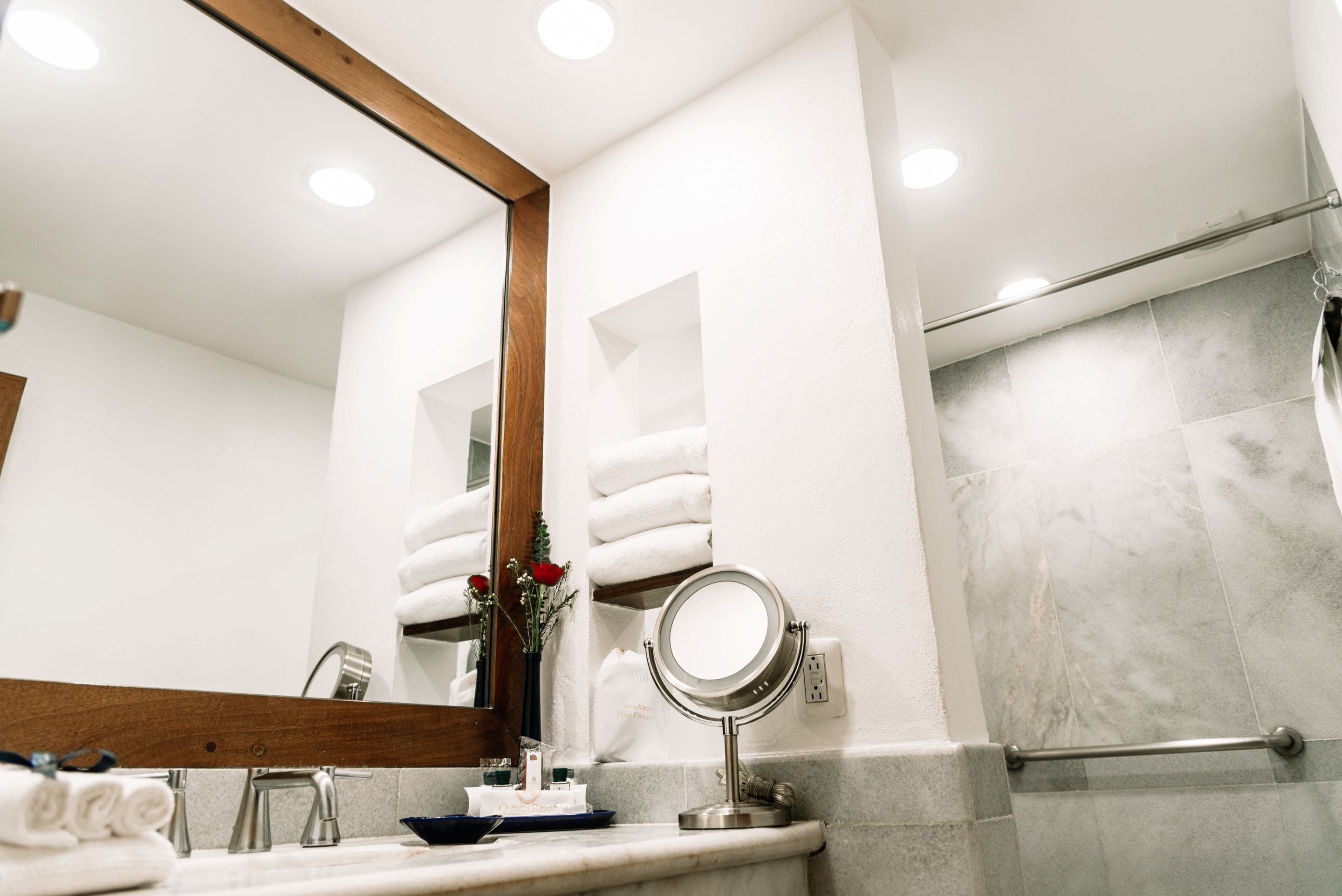 A bathroom with a sink, mirror, towel rack, and shower area.