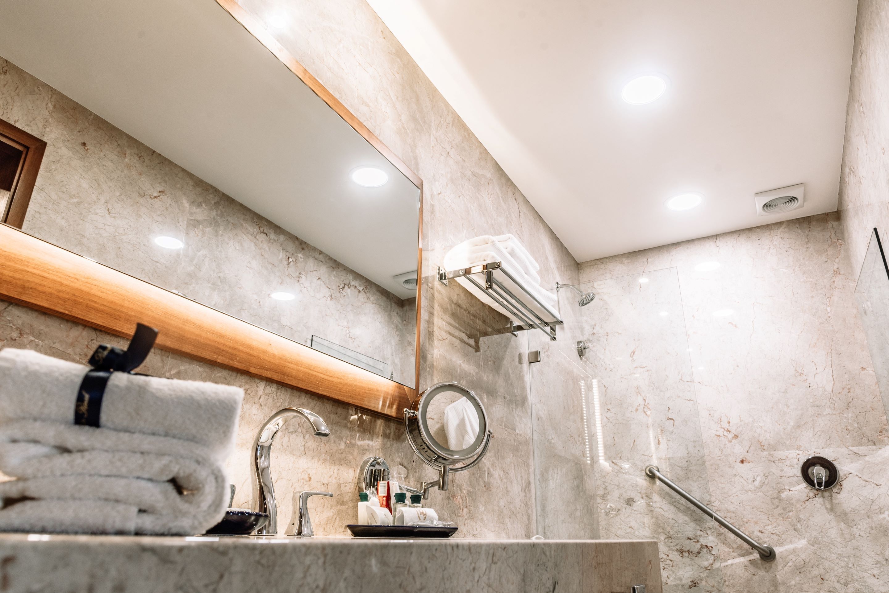 Un baño moderno con lavamanos de mármol, un espejo y un perchero para toallas.
