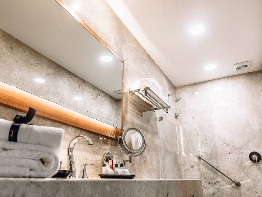 Un baño moderno con lavamanos de mármol, un espejo y un perchero para toallas.