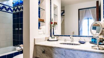 Une salle de bain avec un mur recouvert de carreaux bleus et blancs, un lavabo blanc avec un receveur à motifs noirs et blancs, un miroir et un porte-serviettes.