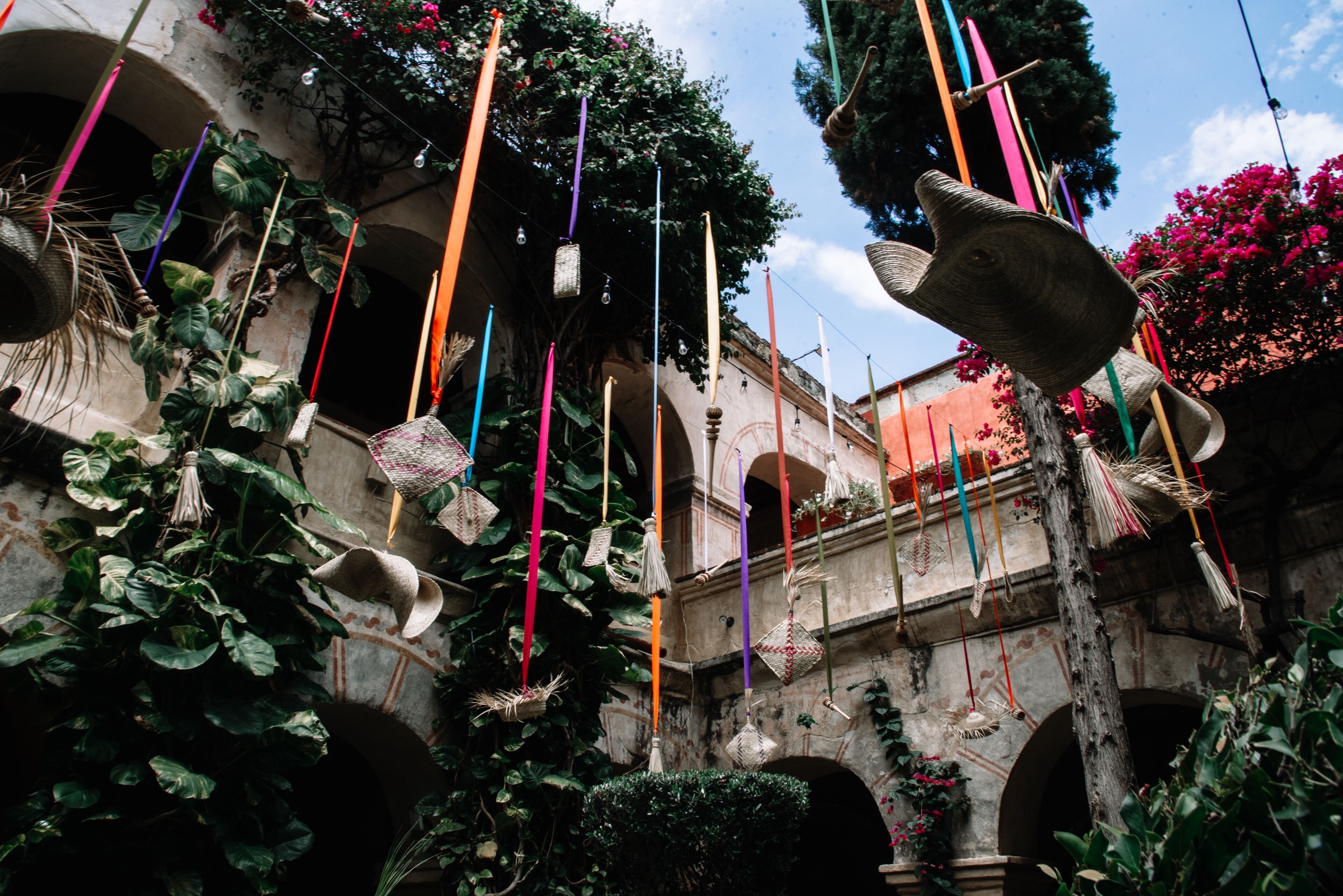 Une cour agrémentée de décorations suspendues, d’un mur en pierre et de plantes en pot.