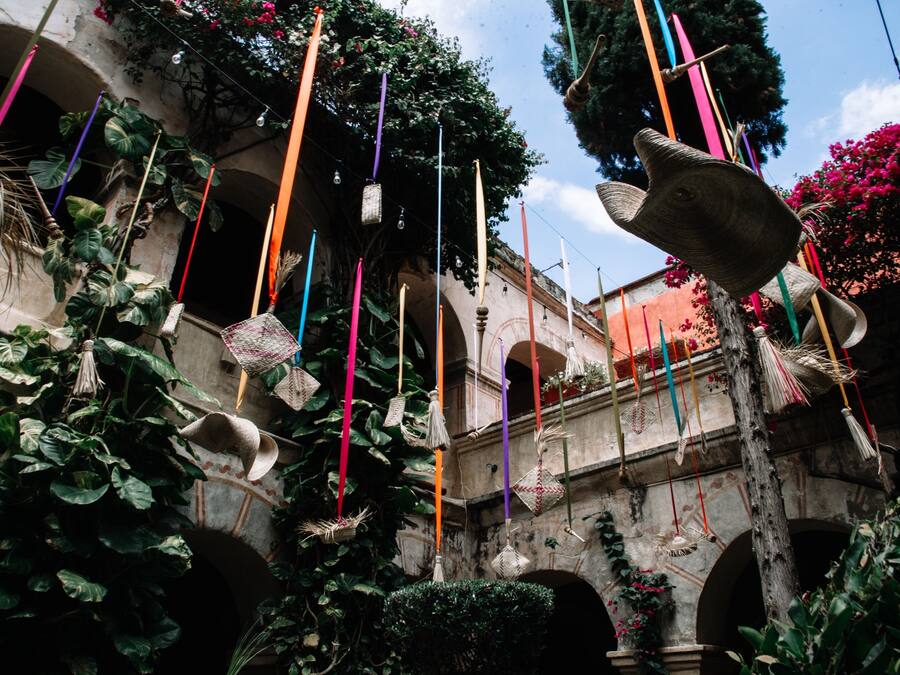 Une cour agrémentée de décorations suspendues, d’un mur en pierre et de plantes en pot.