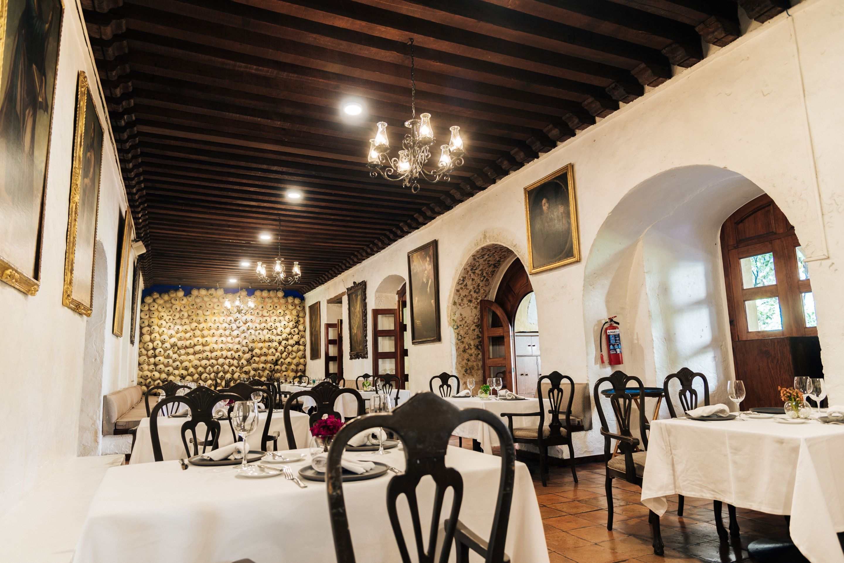 A restaurant with multiple tables, chairs, and a chandelier.