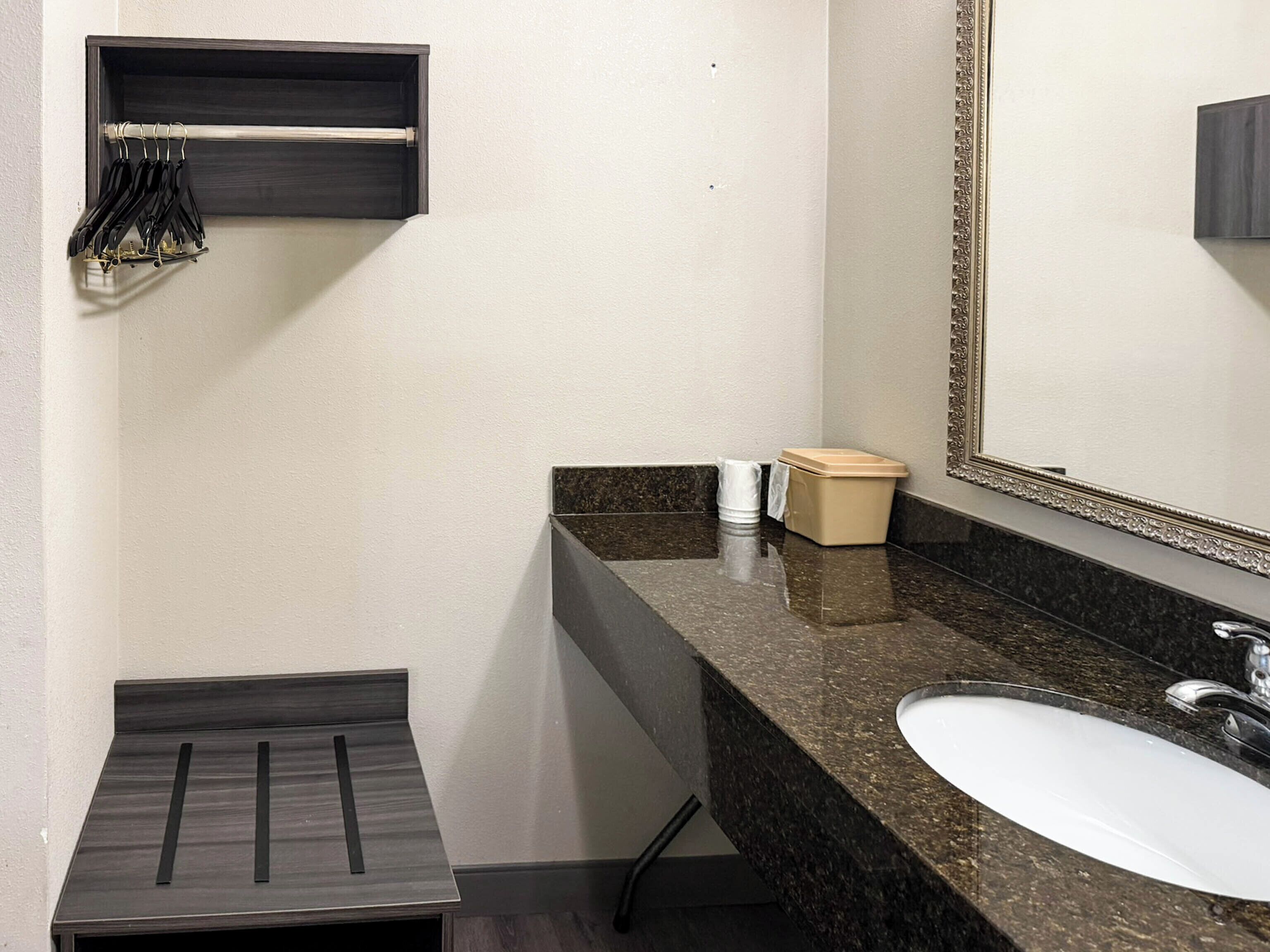 A bathroom with a sink, mirror, towel rack, and a trash bin.
